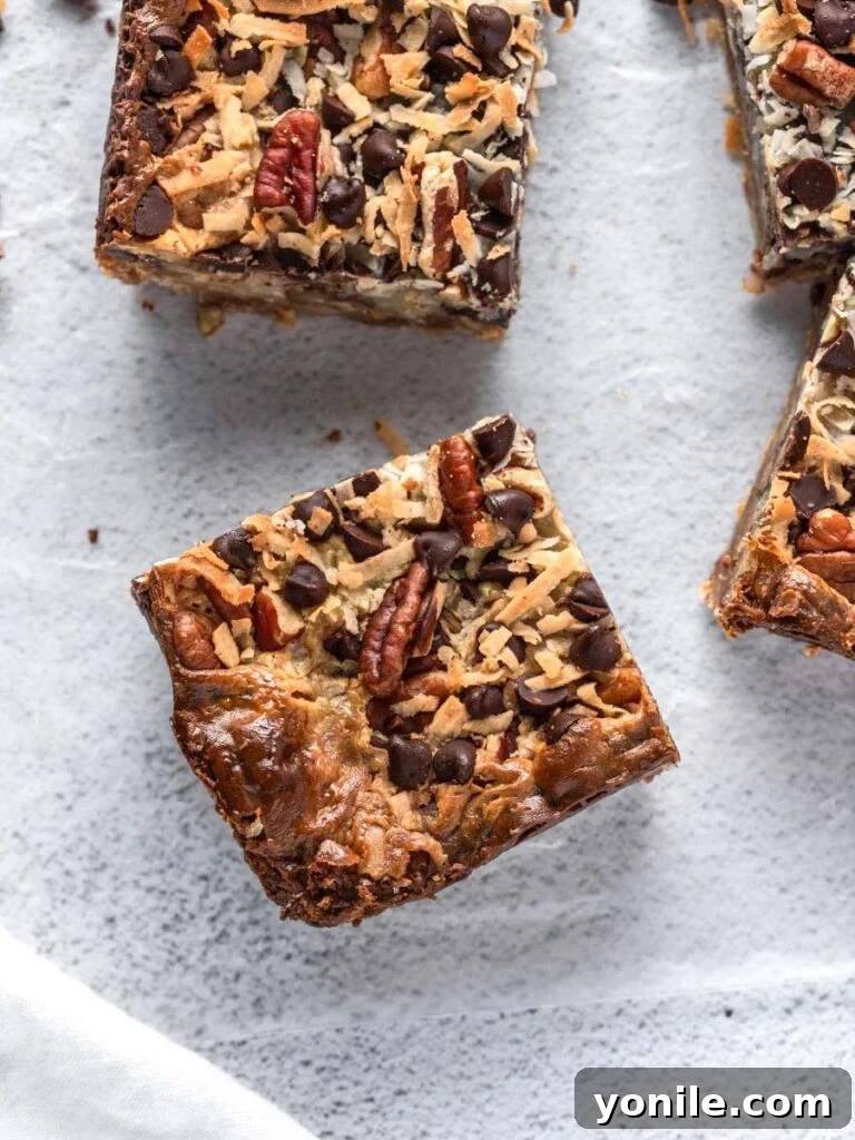 Top down close-up view of golden-brown coconut magic bars, showcasing the layers of coconut, chocolate, and pecans on a graham cracker crust.