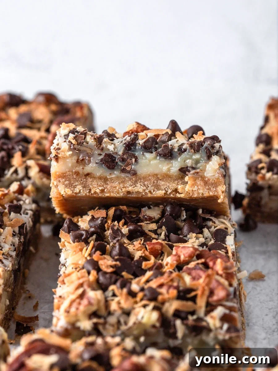 A vibrant display of freshly baked Magic Bars, cut into perfect squares, highlighting the distinct layers of the graham cracker crust, sweet filling, and varied toppings.