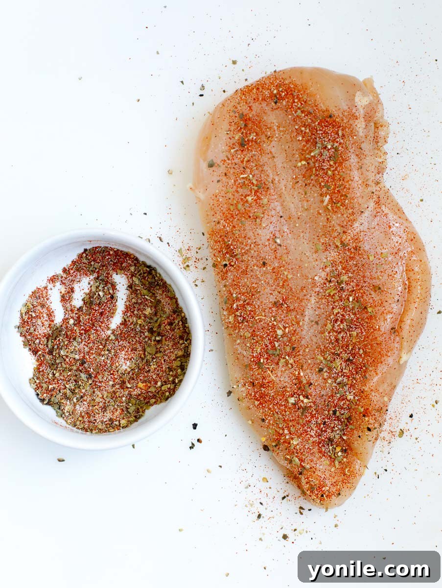 Top down shot of raw chicken breast with seasoning on it and a pocket cut in the side.