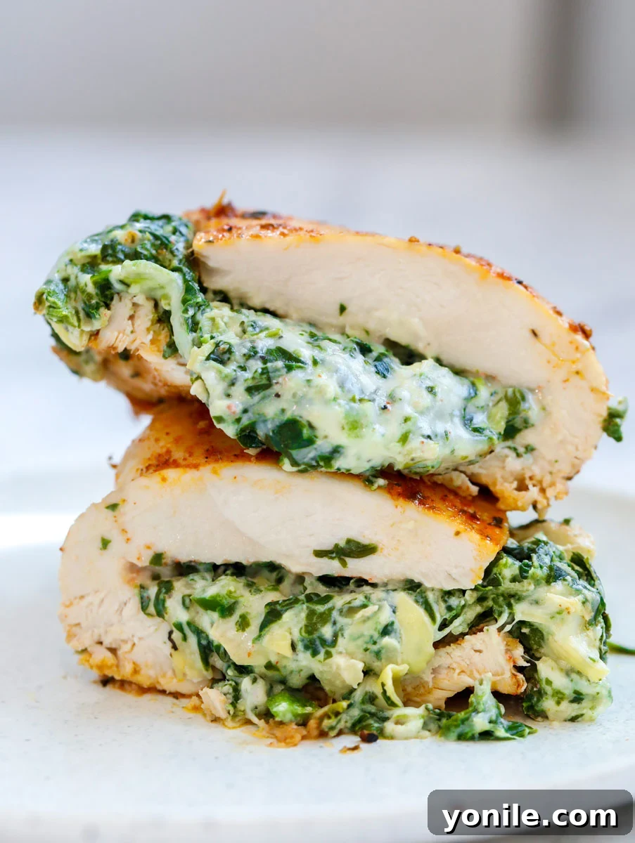 Cheesy spinach stuffed chicken breast cut in half and stacked on top of each other, ready to eat.