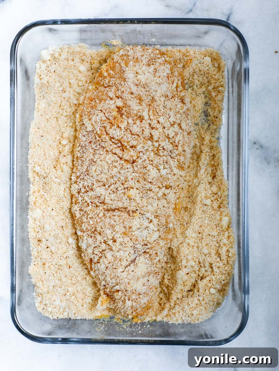 Chicken breast being coated for the second time in the seasoned flour mixture.