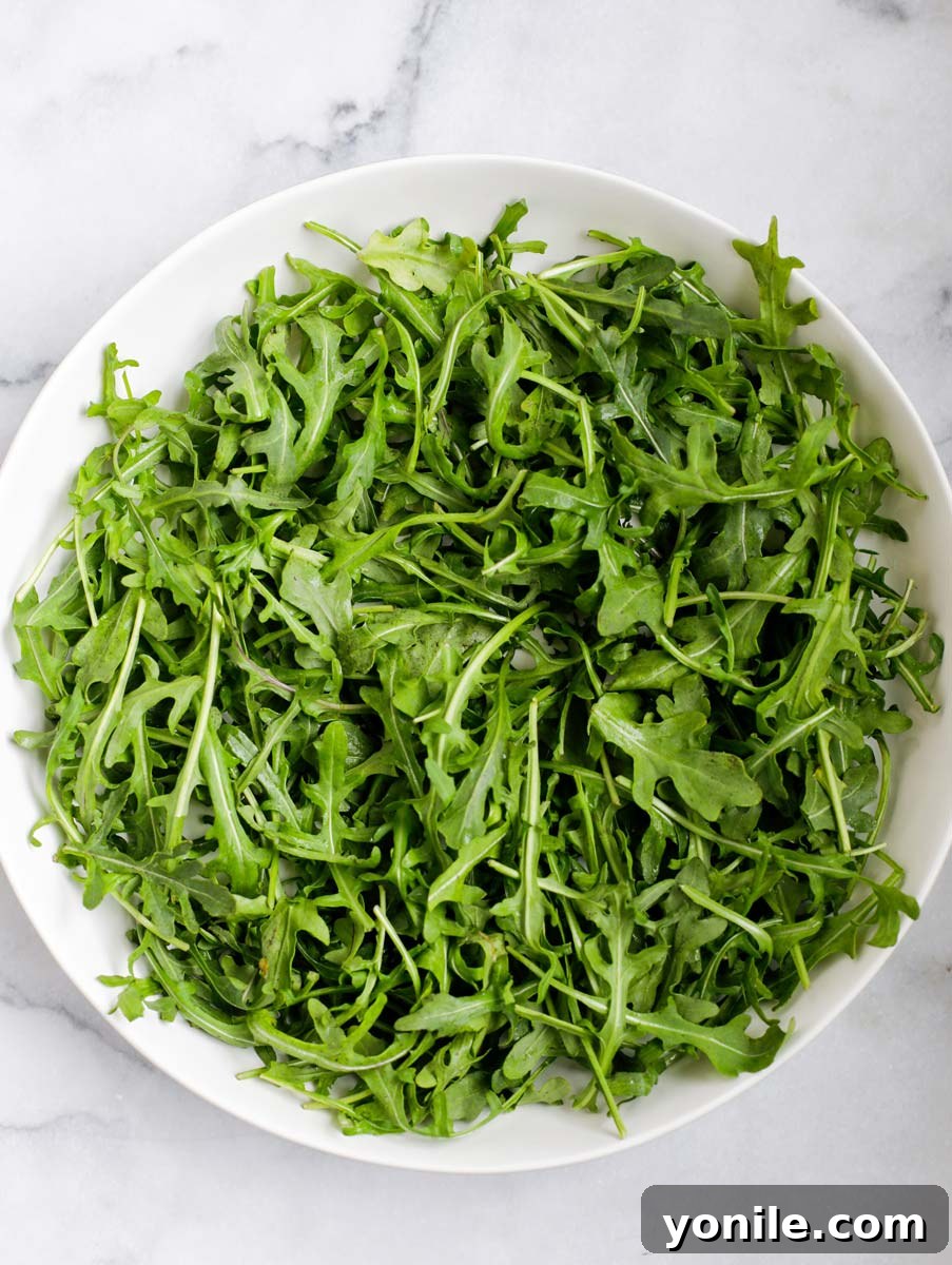 Fresh baby arugula in a mixing bowl, ready to be dressed.