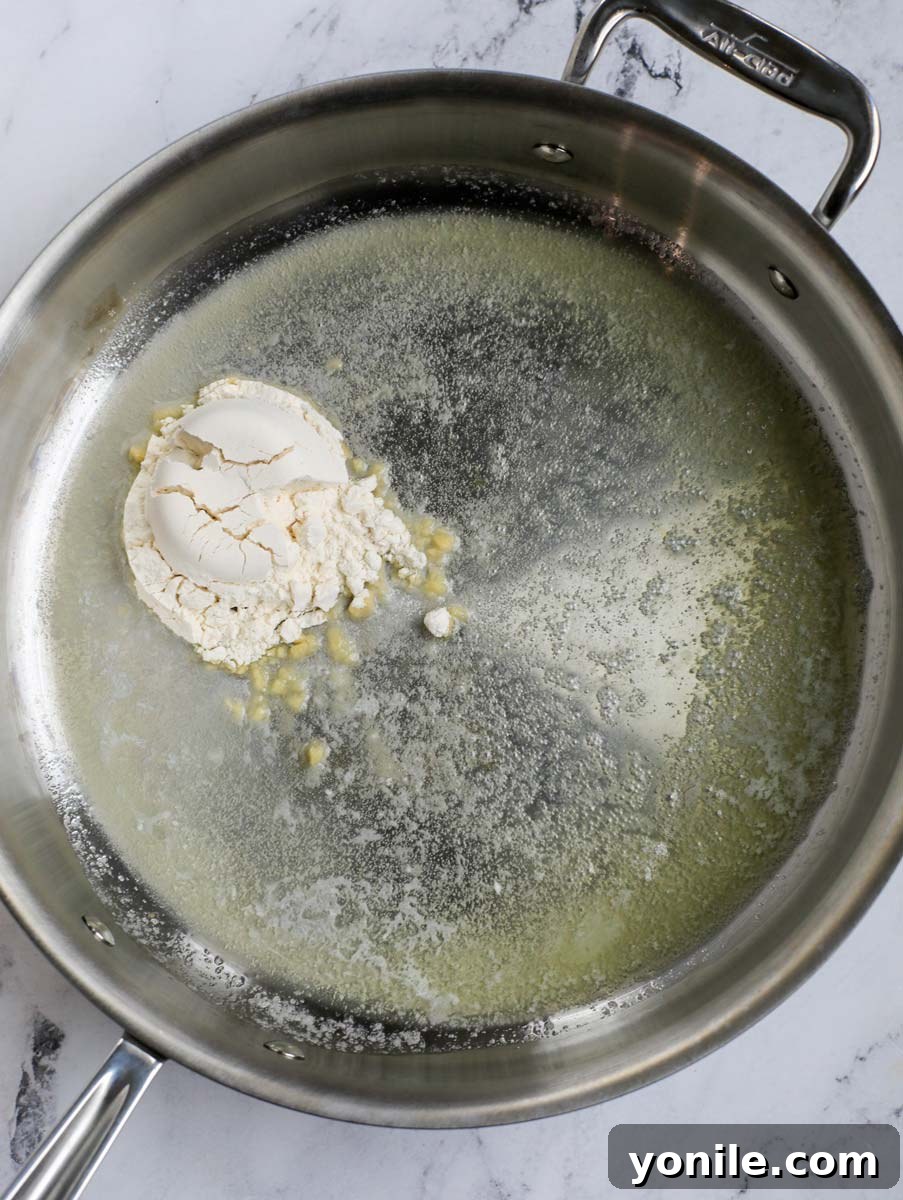 Flour being added to melted butter in a skillet, starting the roux.