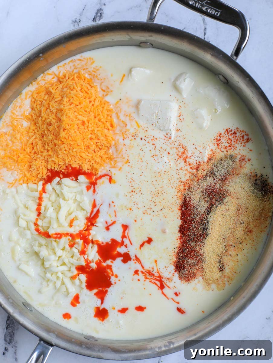Spices, including paprika, garlic powder, and onion powder, being added to the simmering milk sauce.