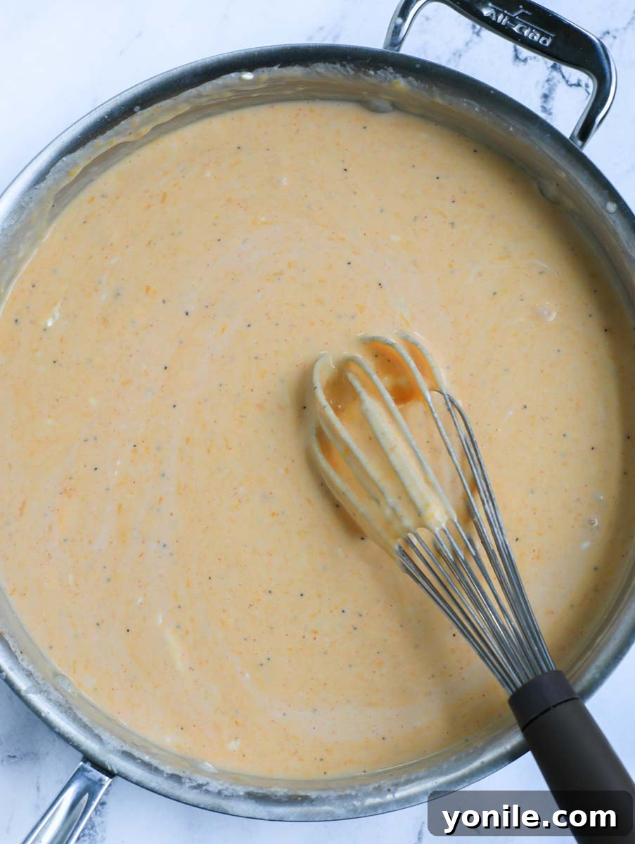 A whisk vigorously combining all the sauce ingredients, including melted cheese and buffalo sauce, for a smooth consistency.