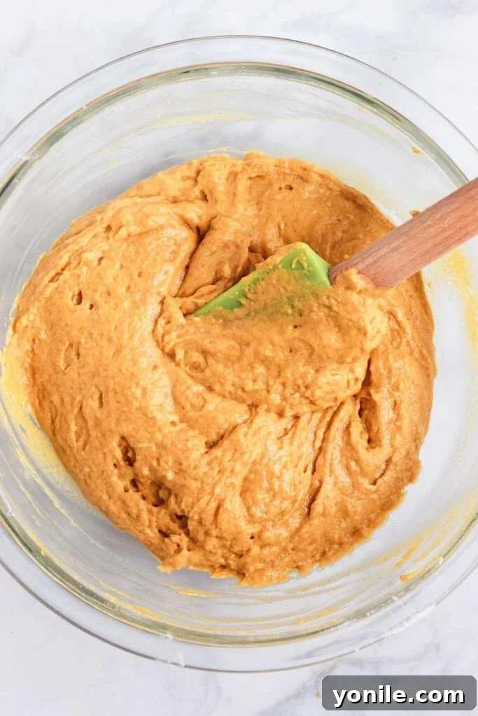 Pumpkin Quick Bread 5 Top down shot of a spatula gently mixing the pumpkin bread batter in a clear glass bowl.
