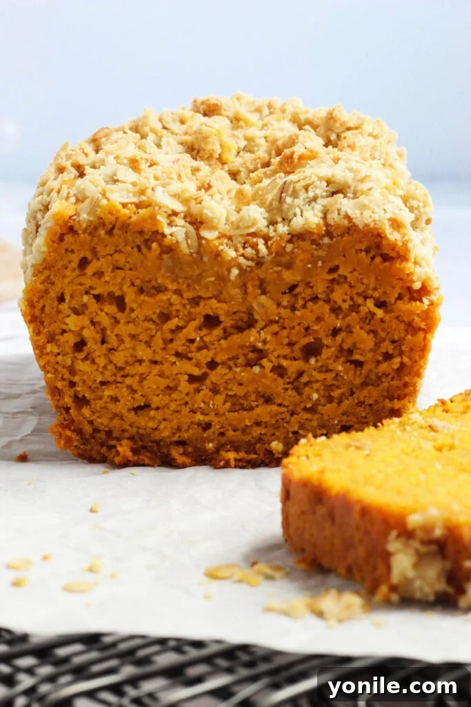 Pumpkin Quick Bread 8 Close up shot of a sliced easy pumpkin bread on a wooden table, showing its moist crumb and streusel.