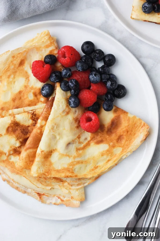 Top down shot of golden crepes on a white plate, ready to be served or filled.