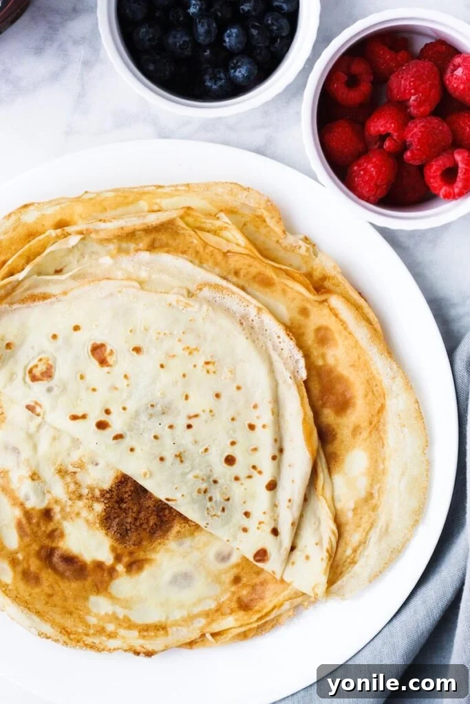 Top down shot of the best crepes stacked on a white plate, ready for serving.