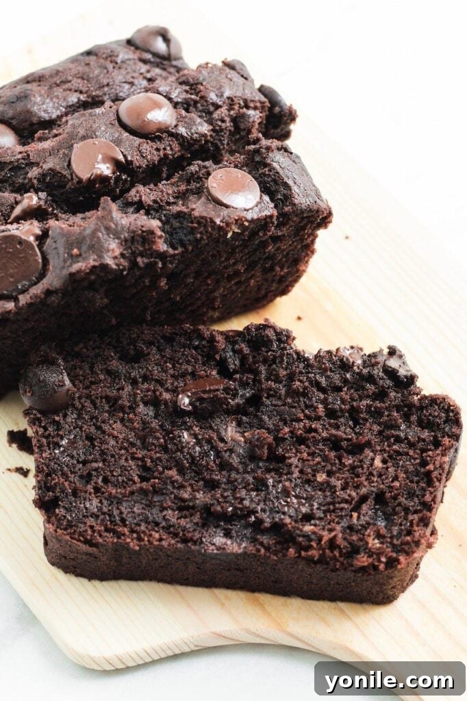 A thick slice of moist chocolate banana bread placed artfully on a small wooden chopping board, ready to be enjoyed.