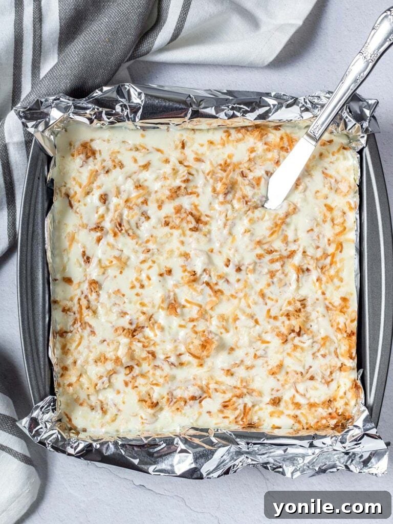 creamy coconut cheesecake filling poured into the baked graham cracker crust in a 9x9 pan, ready for the oven