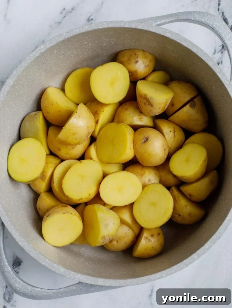 Crispy Oven Roasted Baby Potatoes 3 Top down shot of halved baby potatoes in a white bowl, ready for cooking.
