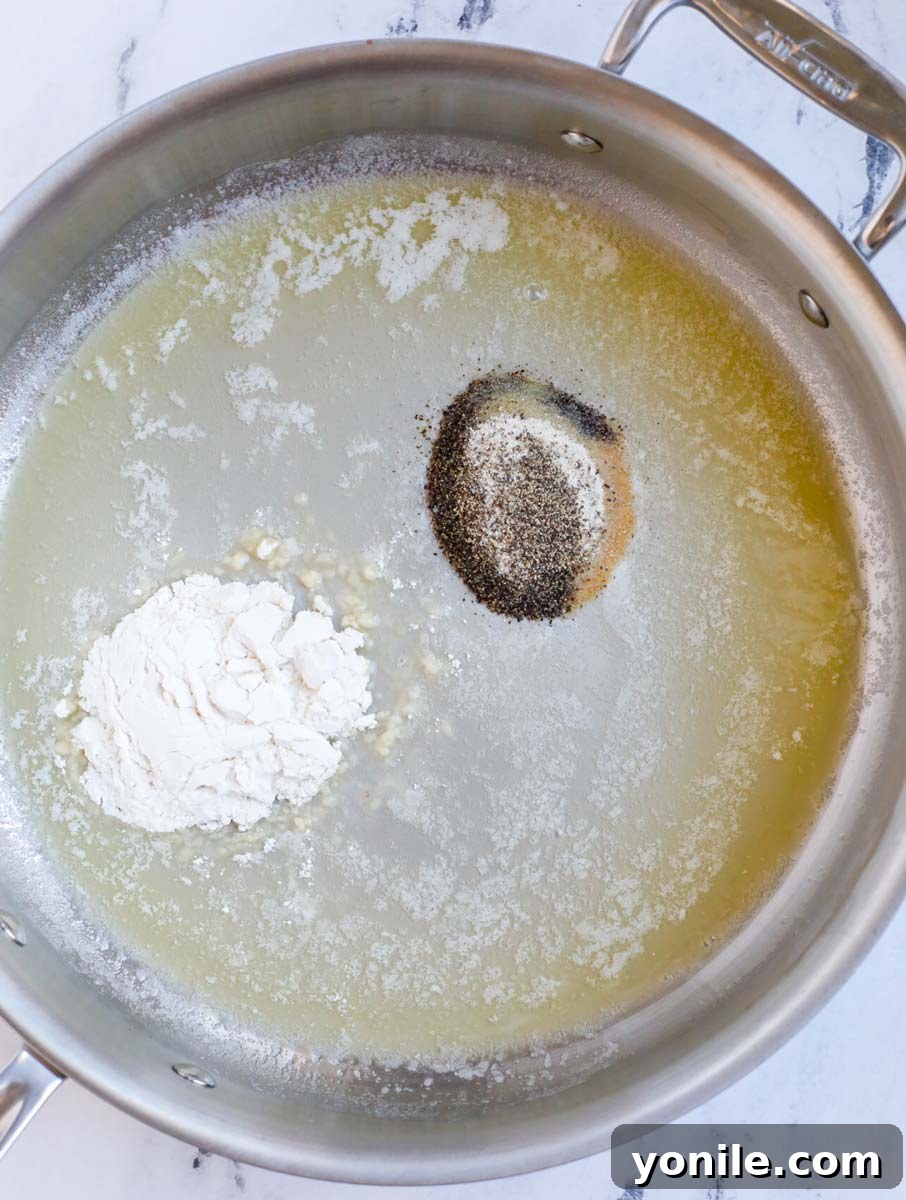 Melted butter, olive oil, spices, and flour combined in a silver skillet, forming a rich roux for the casserole sauce.