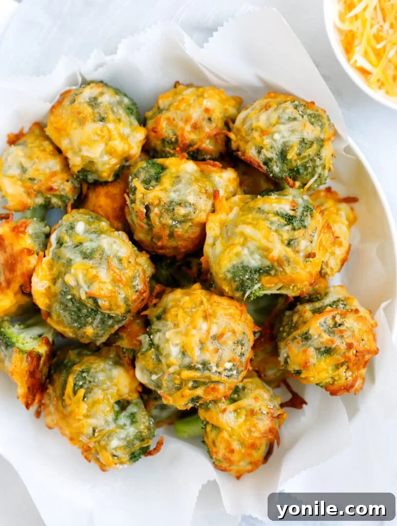 Golden Broccoli Cheese Poppers 2 Overhead shot of cheesy broccoli bites on a white bowl.