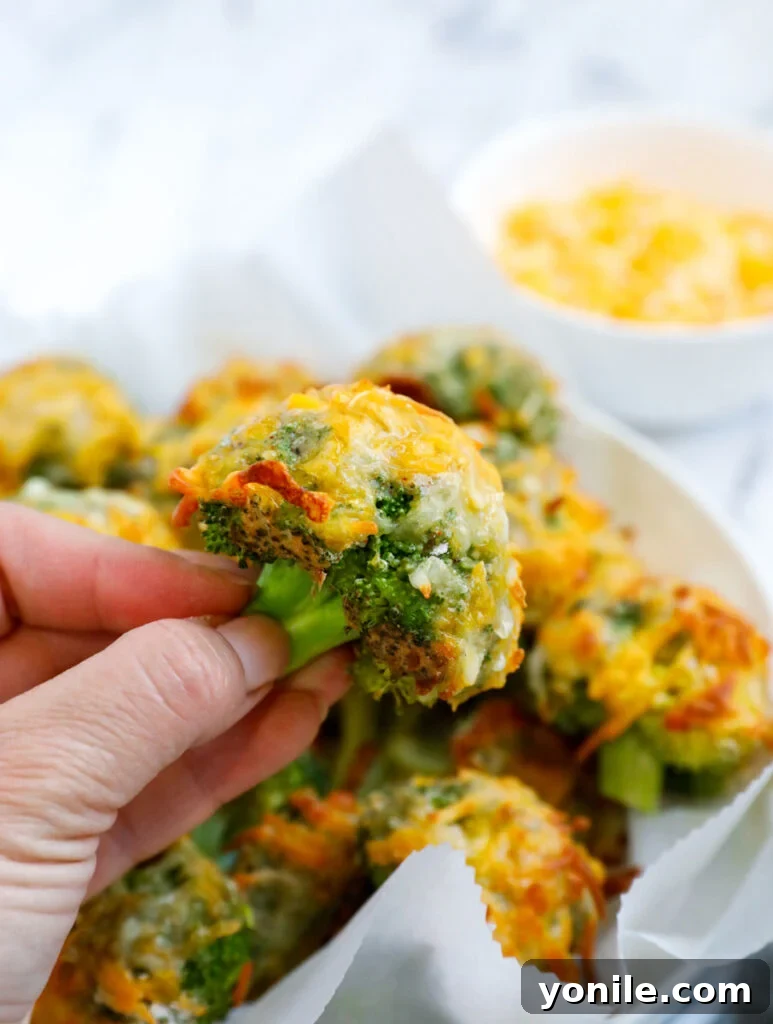 Golden Broccoli Cheese Poppers 9 Hand holding a cheesy broccoli bite.