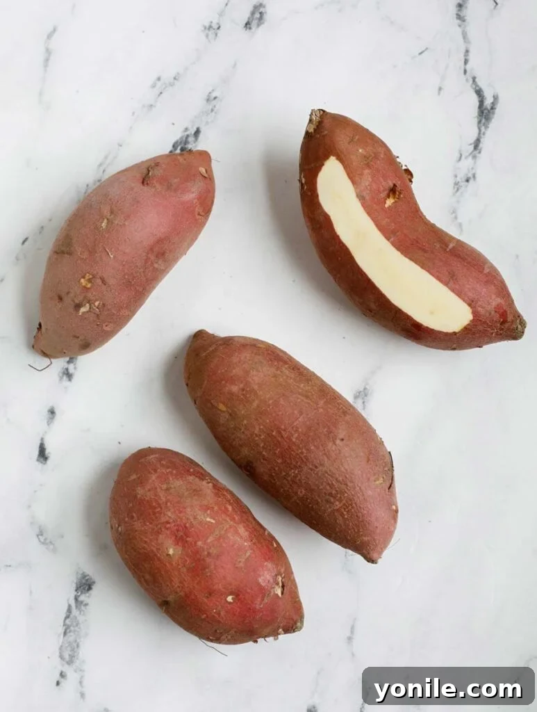 Fresh Japanese sweet potatoes on a wooden surface.