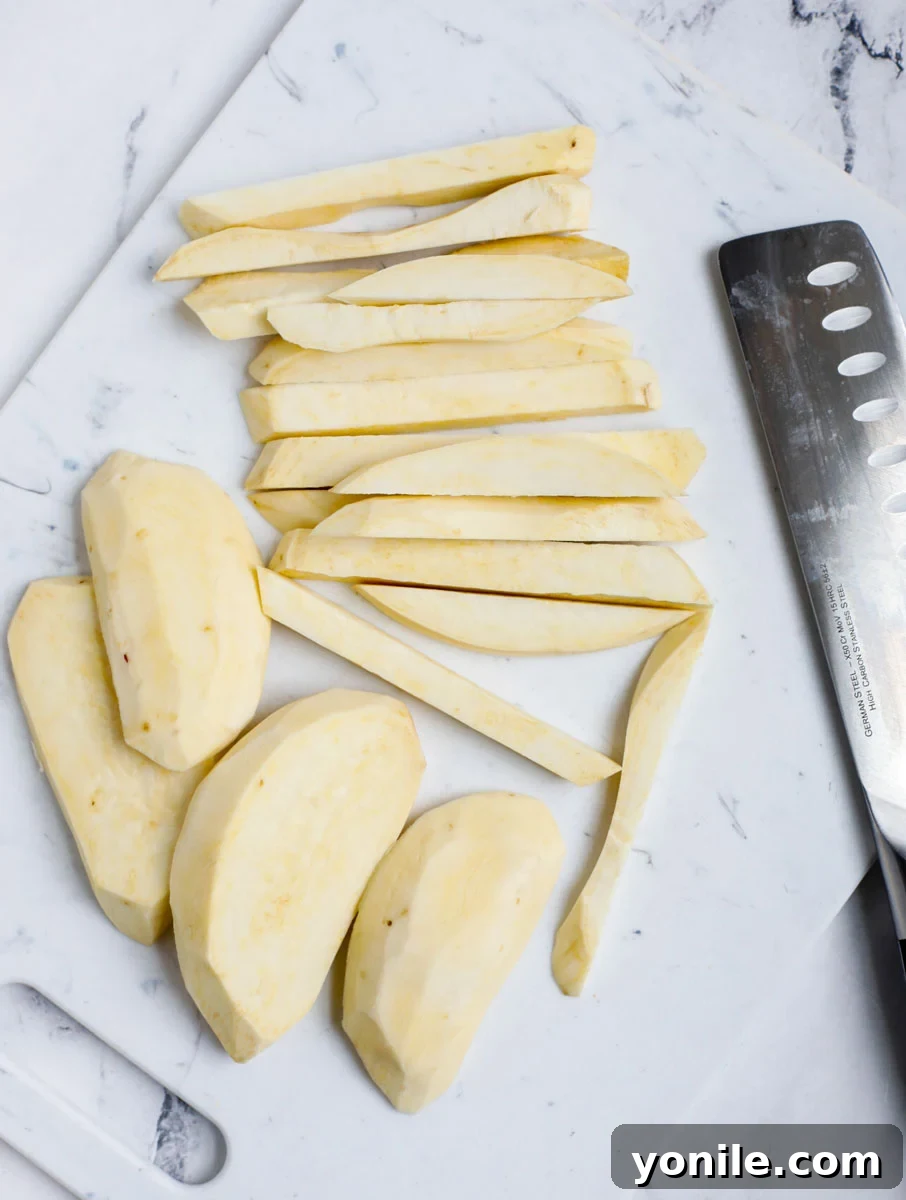 Slices of sweet potato being cut next to a knife on a cutting board.