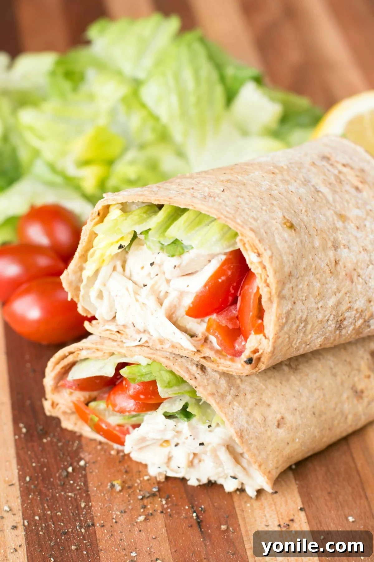 Effortless Chicken Caesar Wraps 3 Close up picture of a chicken caesar wrap sliced in half on a cutting board, showcasing fresh ingredients