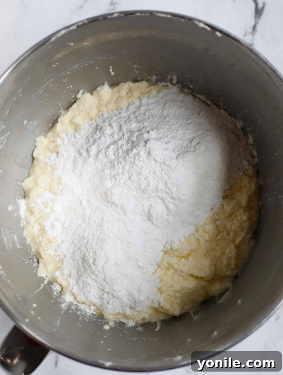 The flour mixture being gradually incorporated into the wet ingredients, showing a thickening batter.