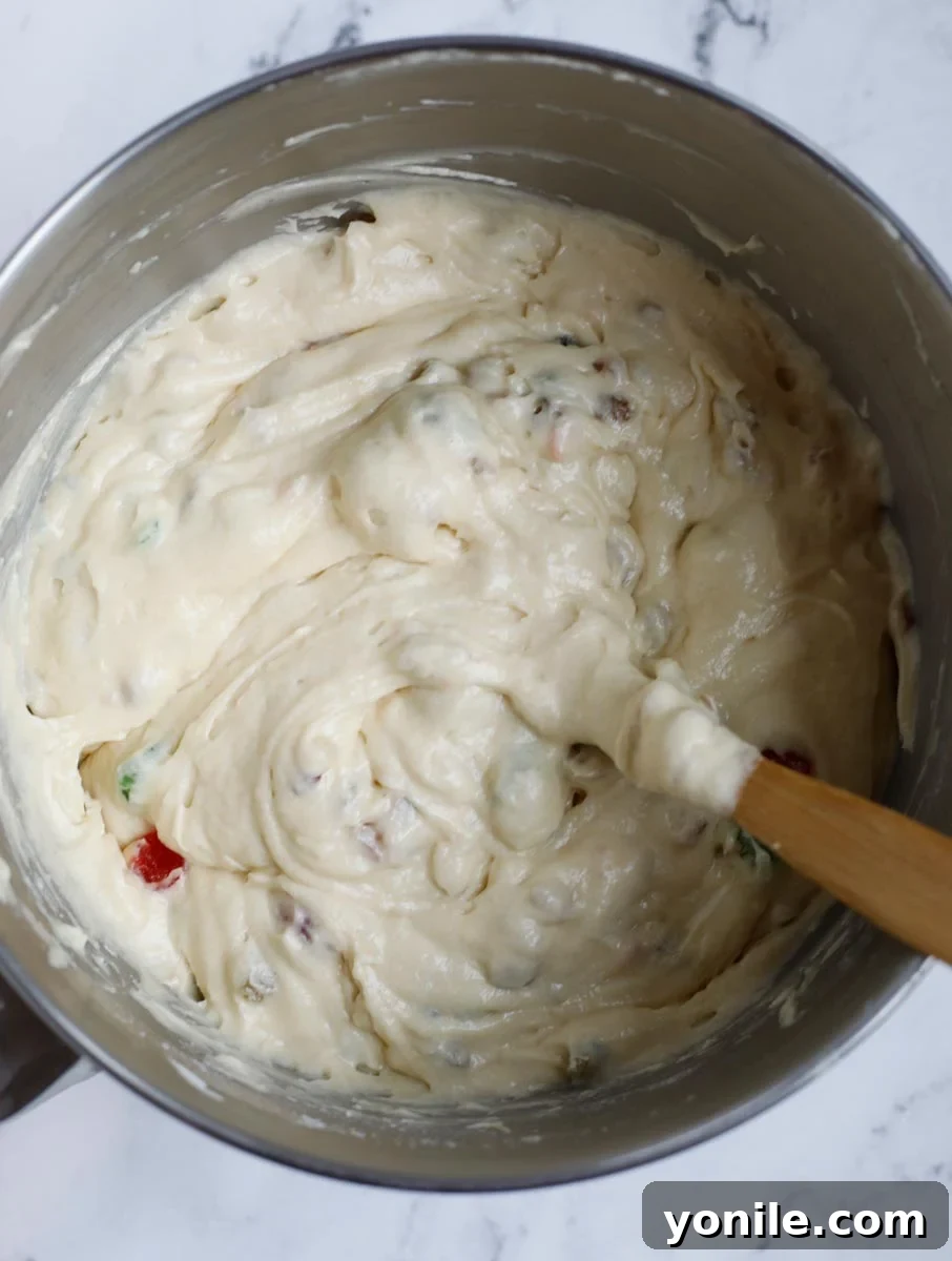 The cake batter with the dried fruits evenly mixed in, showing a rich, colorful consistency.