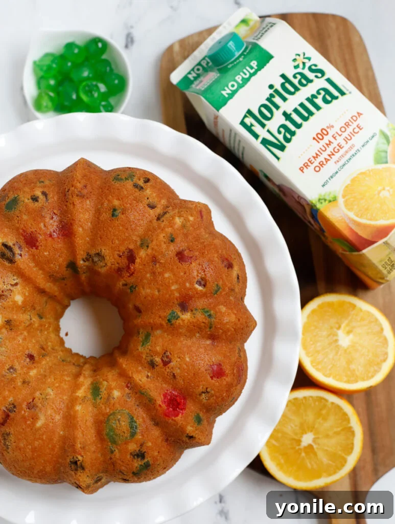 A beautifully decorated orange fruit cake, elegantly served on a white dish, ready to be enjoyed.