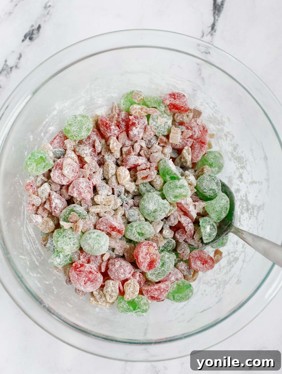 Dried fruits lightly dusted with flour in a bowl, demonstrating the crucial step to prevent sinking during baking.