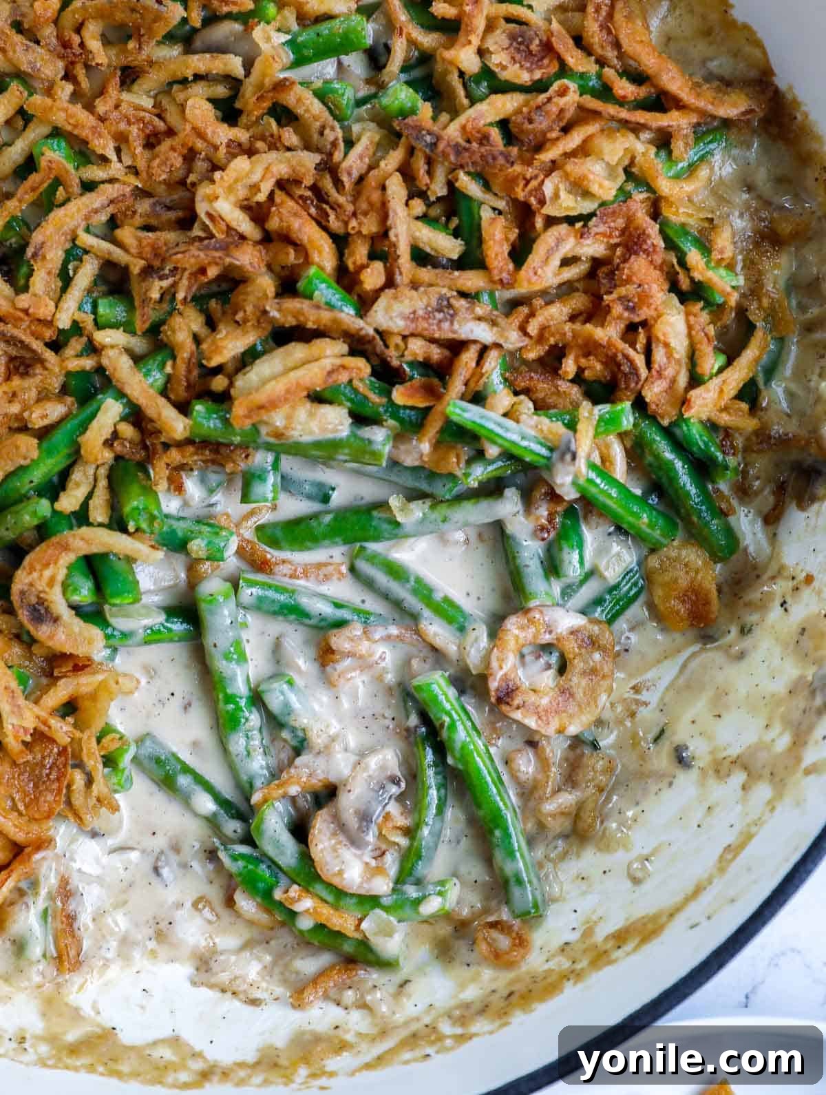 Homemade Green Bean Casserole with a portion removed, showcasing its creamy texture and crispy topping.