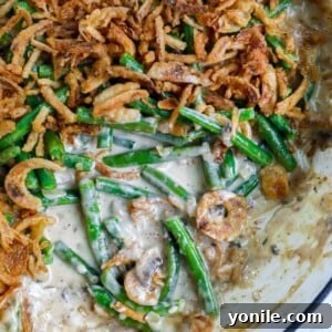 Homemade Green Bean Casserole with a portion removed, showcasing its creamy texture and crispy topping.