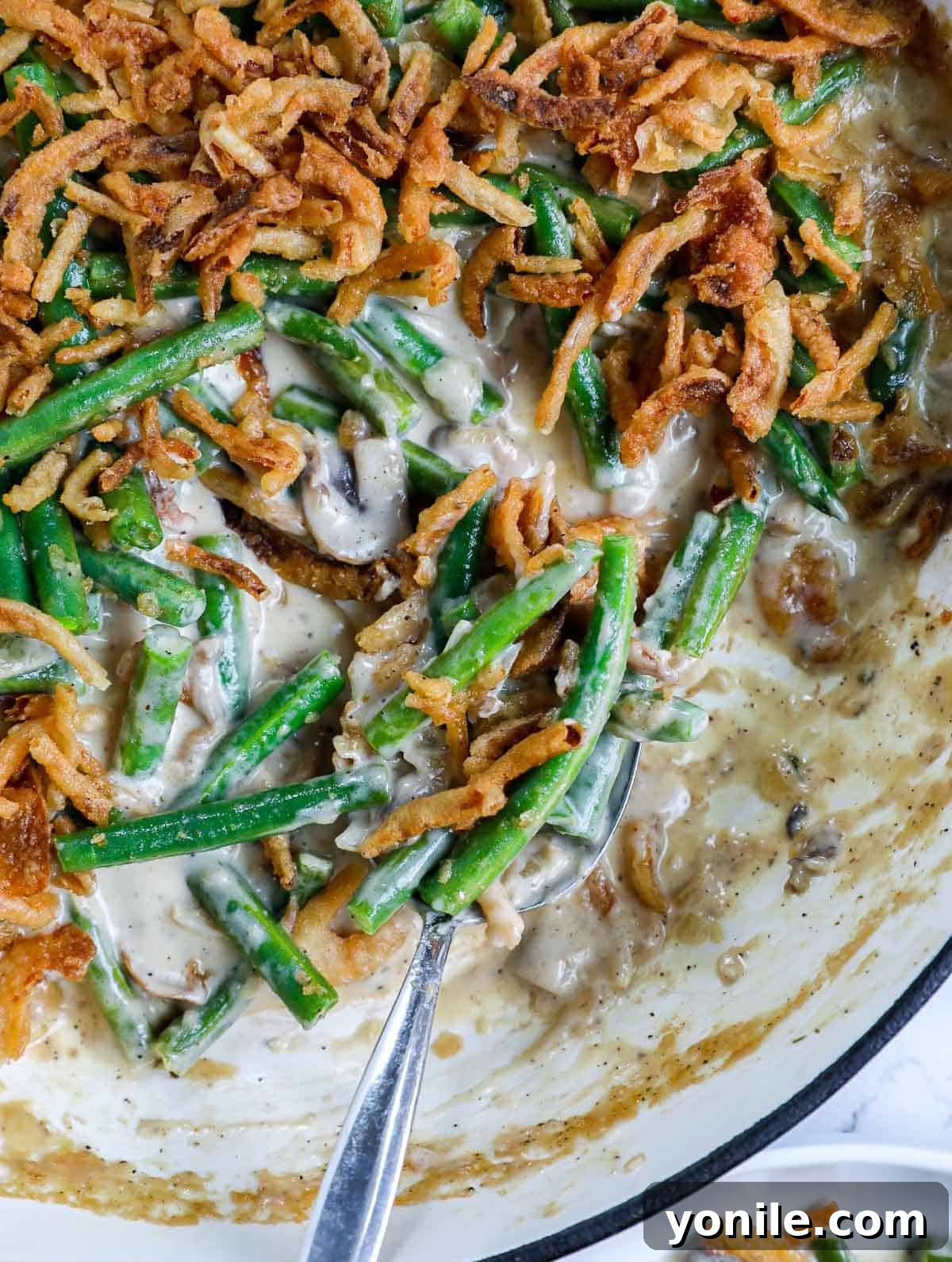 Close-up of a serving spoon scooping into the rich, creamy homemade green bean casserole, highlighting its delicious layers.