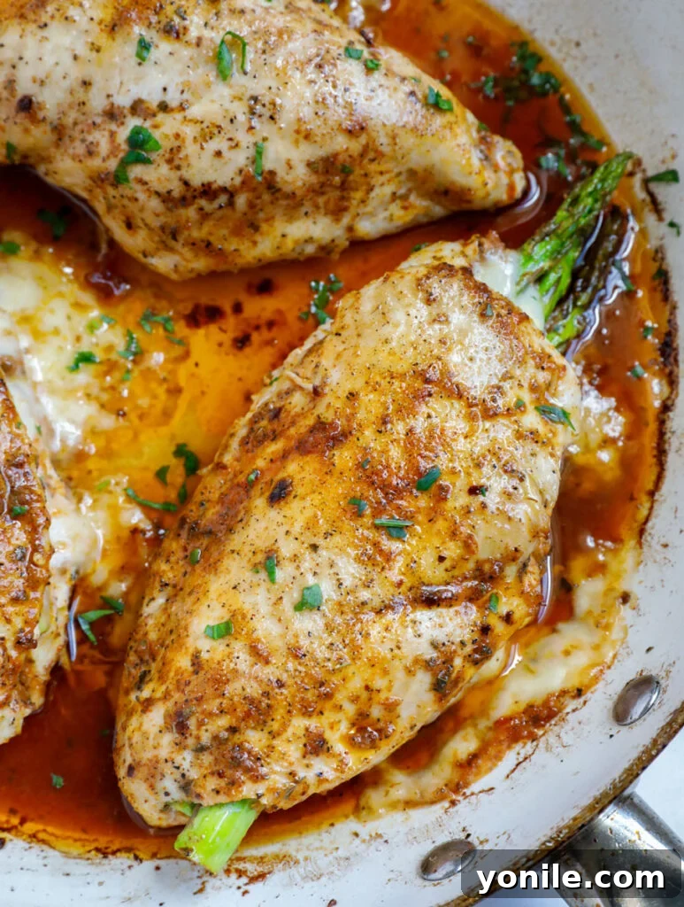 Top down shot of asparagus stuffed chicken breasts in a skillet.