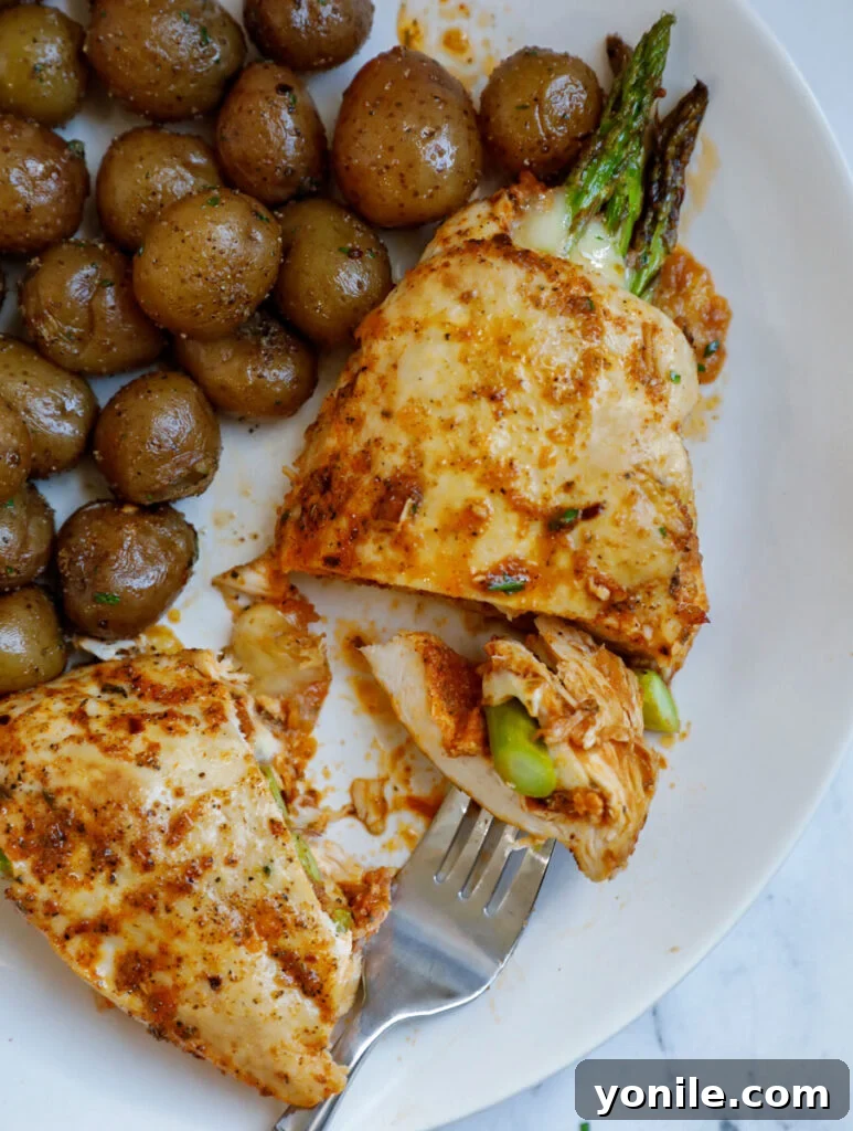 Top down shot of asparagus stuffed chicken with potatoes on the side. 