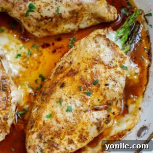Top down shot of asparagus stuffed chicken breasts in a skillet.