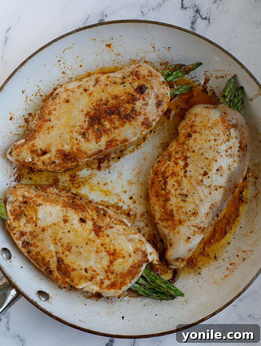 Three stuffed chicken breast in a skillet.