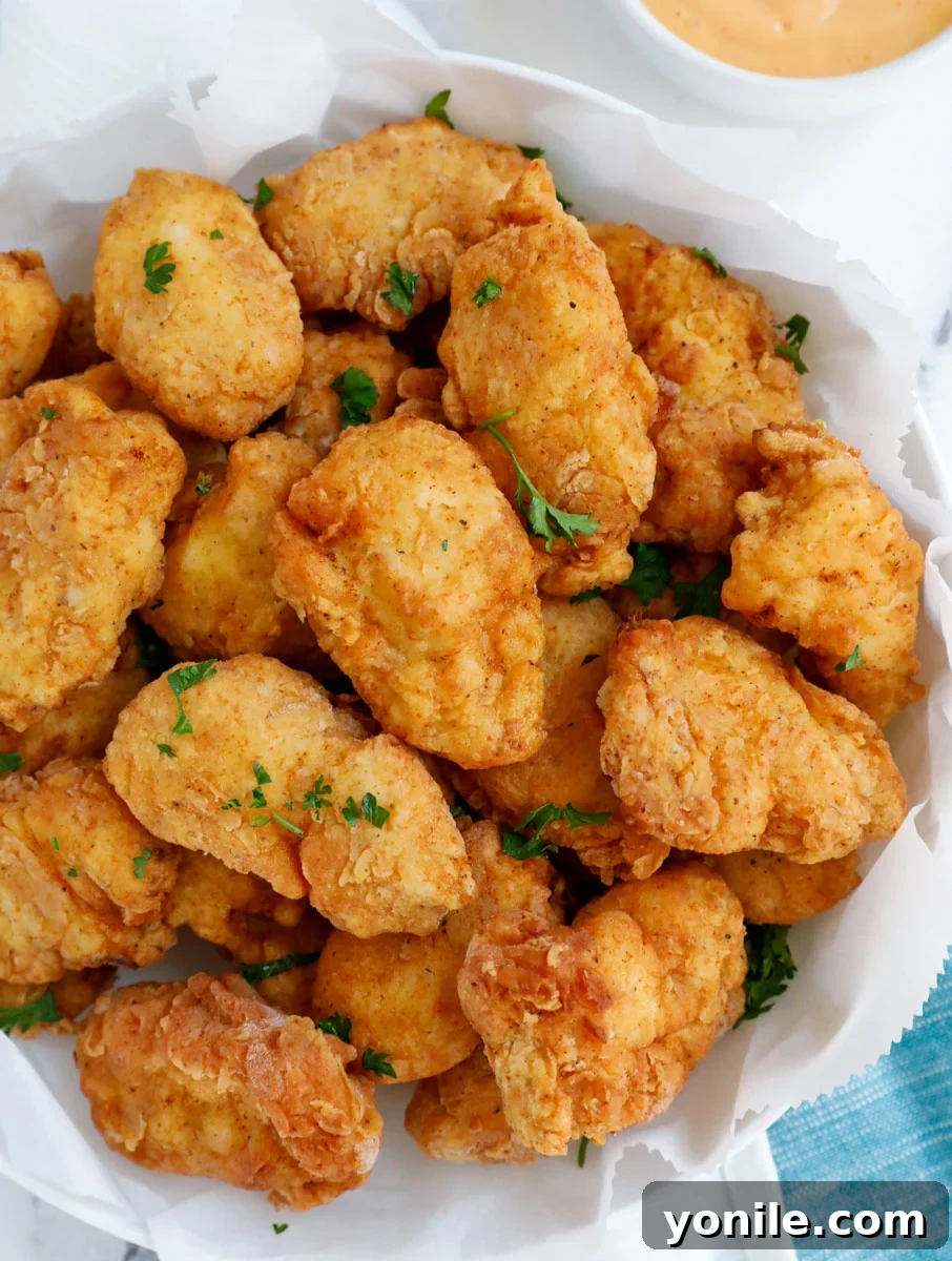 Homemade Chicken Nuggets: Crispy, Juicy, Perfect 8 Top down view of homemade chicken nuggets on a white plate with a side of creamy dipping sauce.