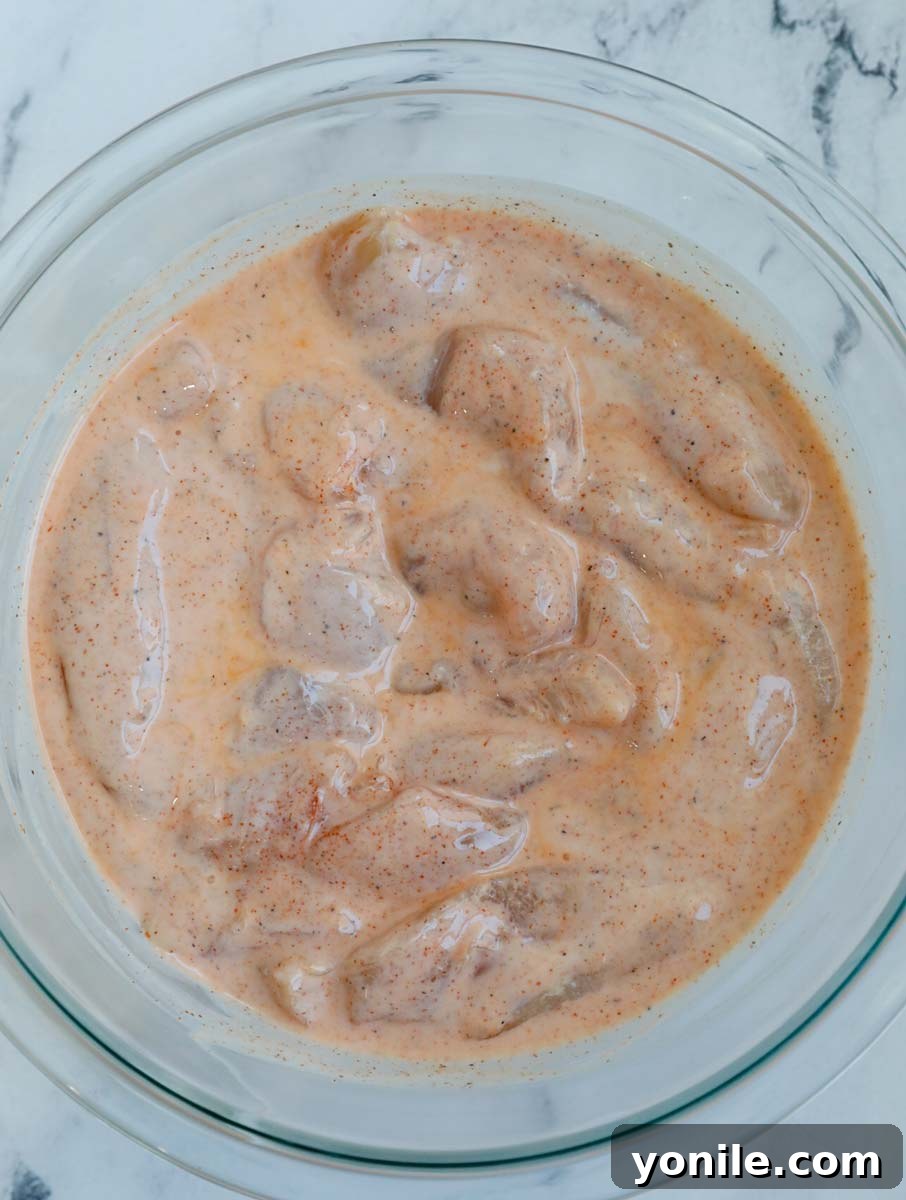 Overhead shot of chicken tenders marinating in a bowl, absorbing flavorful liquid.