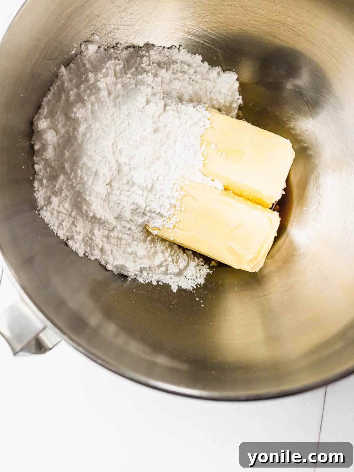 The Danish butter cookie dough, a creamy yellow mixture, in a large mixing bowl with an electric mixer paddle attachment, ready for the next step.