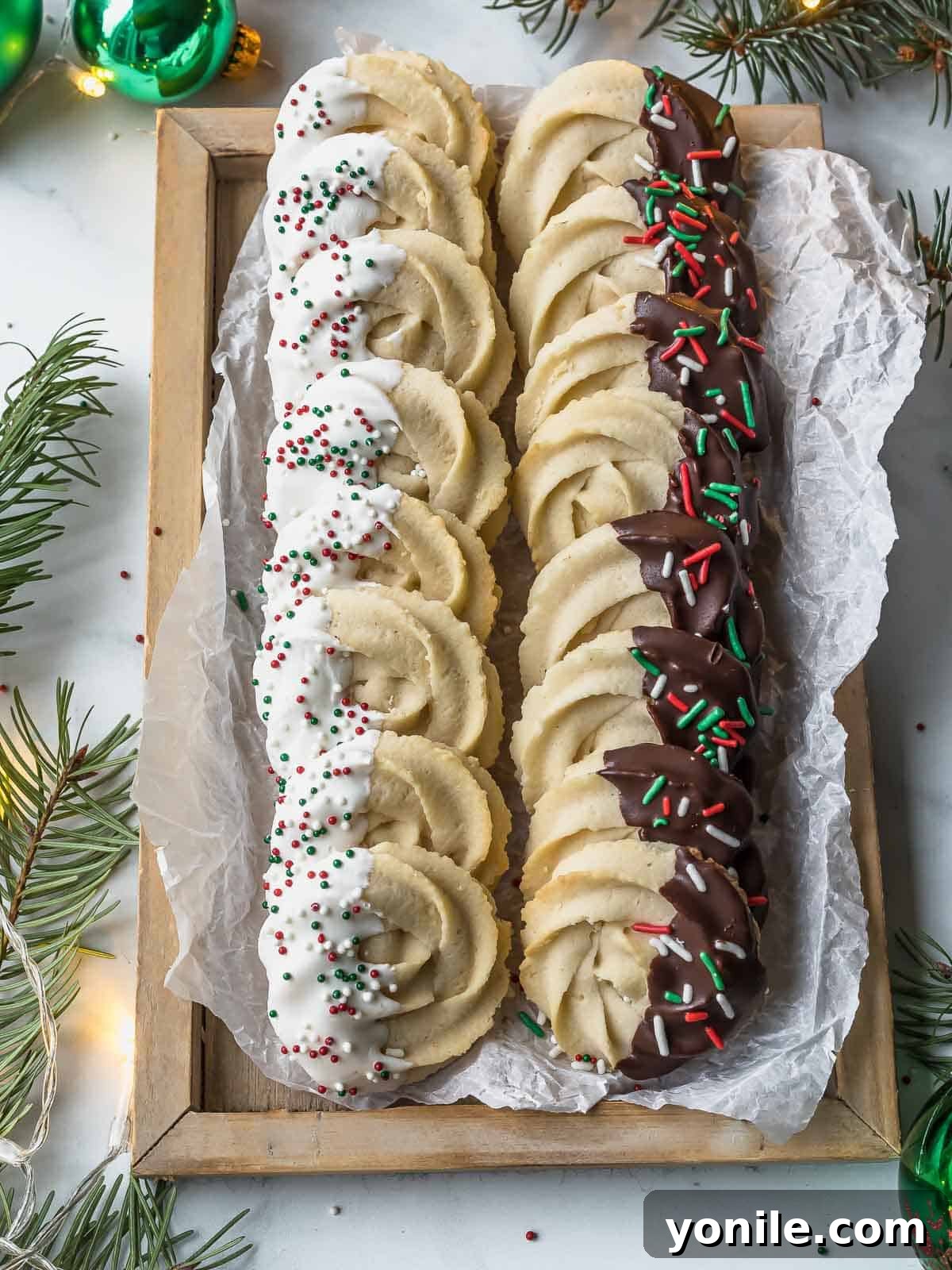 A charming wooden platter showcasing a variety of homemade Danish butter cookies, some plain and some elegantly dipped in chocolate with sprinkles, perfect for a cozy gathering.