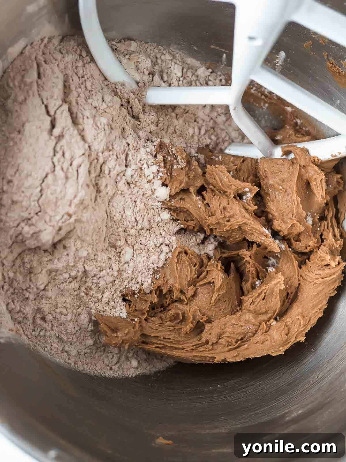 wet and dry ingredient cookie dough coming together in a bowl