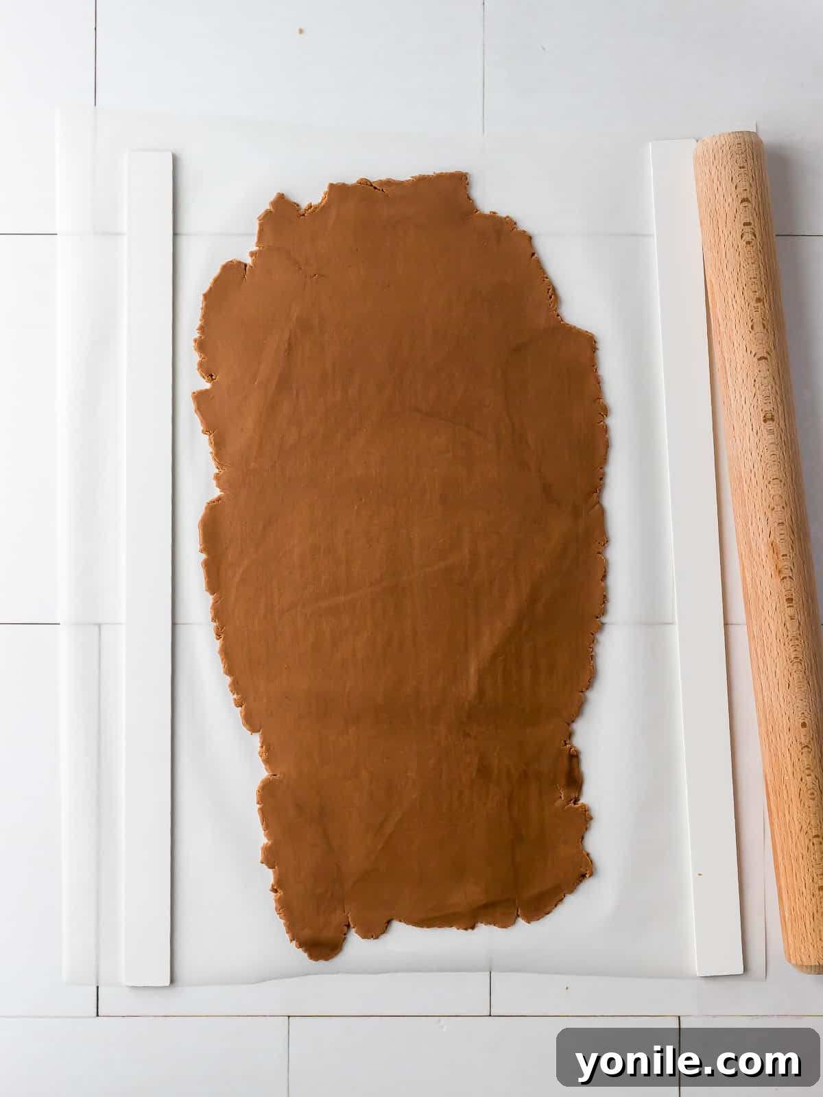gingerbread cookie dough rolled out between parchment paper