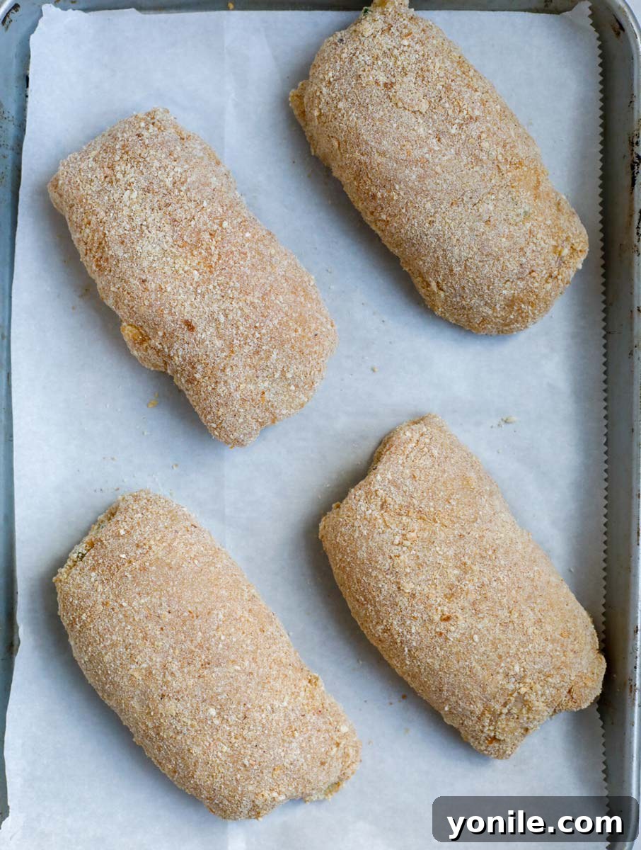 Creamy Jalapeño Chicken Popper 12 Top down shot of several jalapeno popper chicken rolls arranged on a baking sheet, ready for the oven.