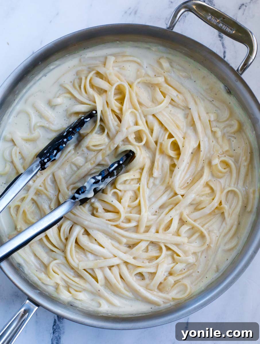 Mixing pasta into the creamy sauce.