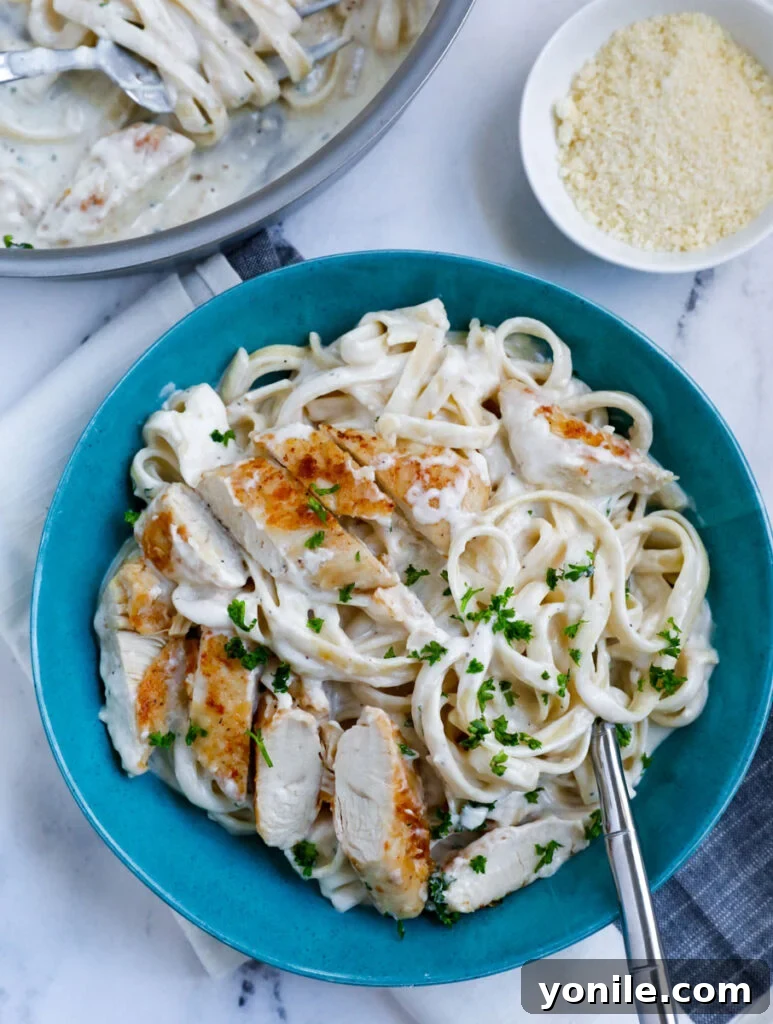 Overhead shot of creamy chicken alfredo pasta on a blue plate. 