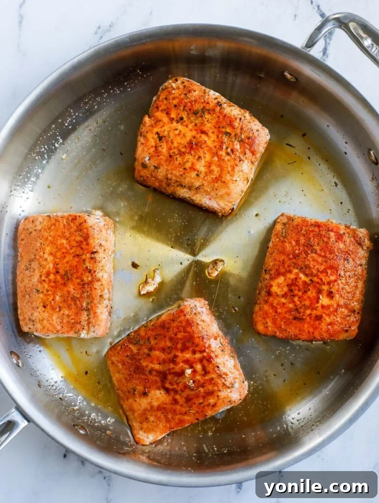 Pan searing the salmon in a pan to create a crispy skin.