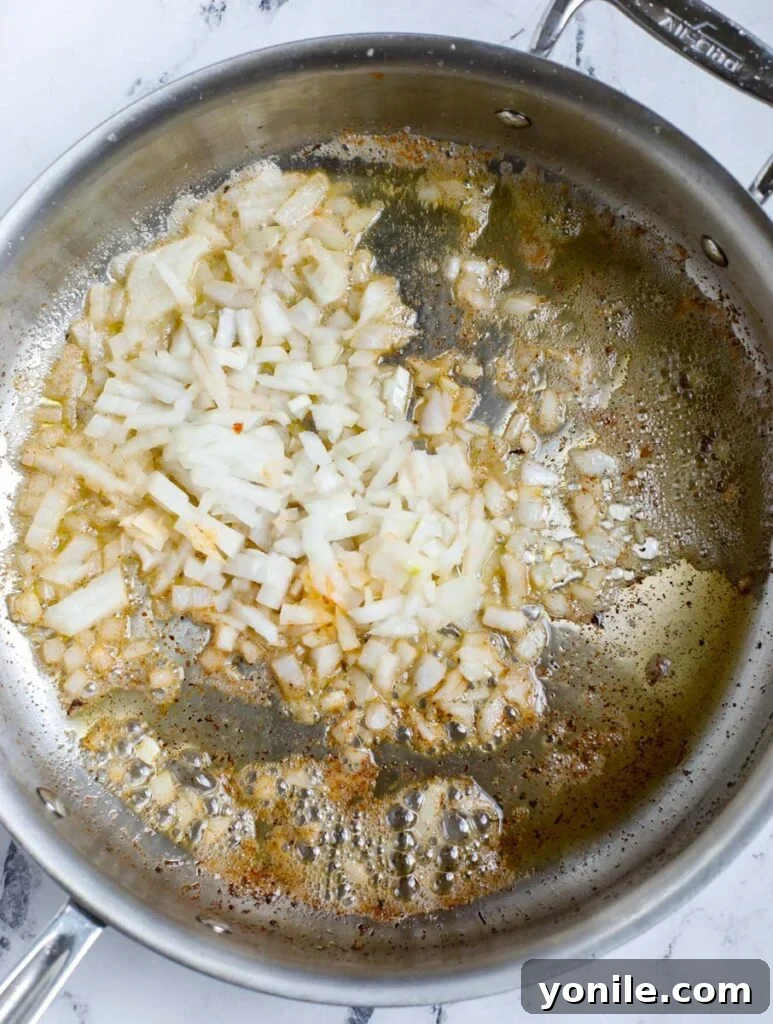Top down view of sautéed onion in a skillet.