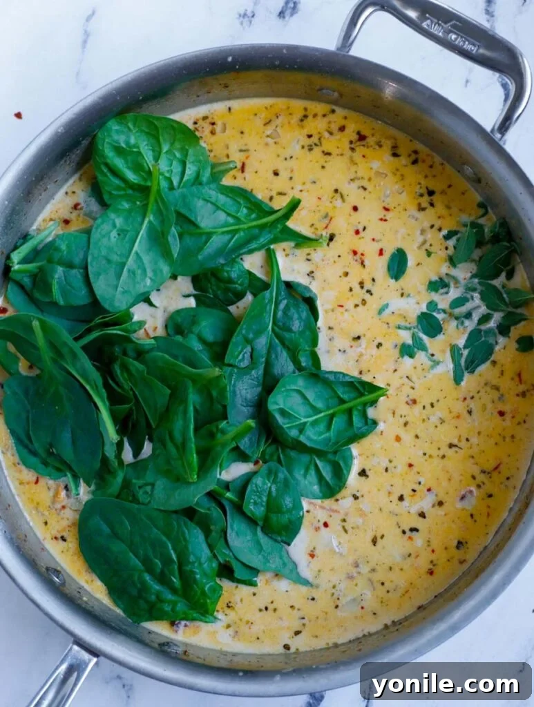 Fresh spinach being added to the cream sauce.