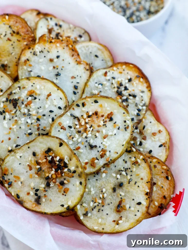 Everything Bagel Chips 2 A top-down shot of golden-brown, crispy Everything Bagel Potato Chips served elegantly in a rustic basket, highlighting their appealing texture and savory seasoning.