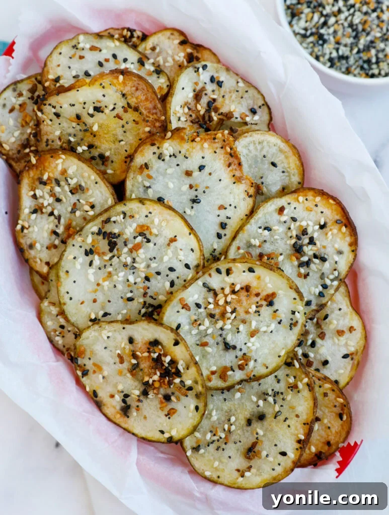 Everything Bagel Chips 6 An overhead shot showcasing a generous serving of crispy, golden-brown Everything Bagel Potato Chips nestled in a stylish basket, highlighting their texture and seasoning.