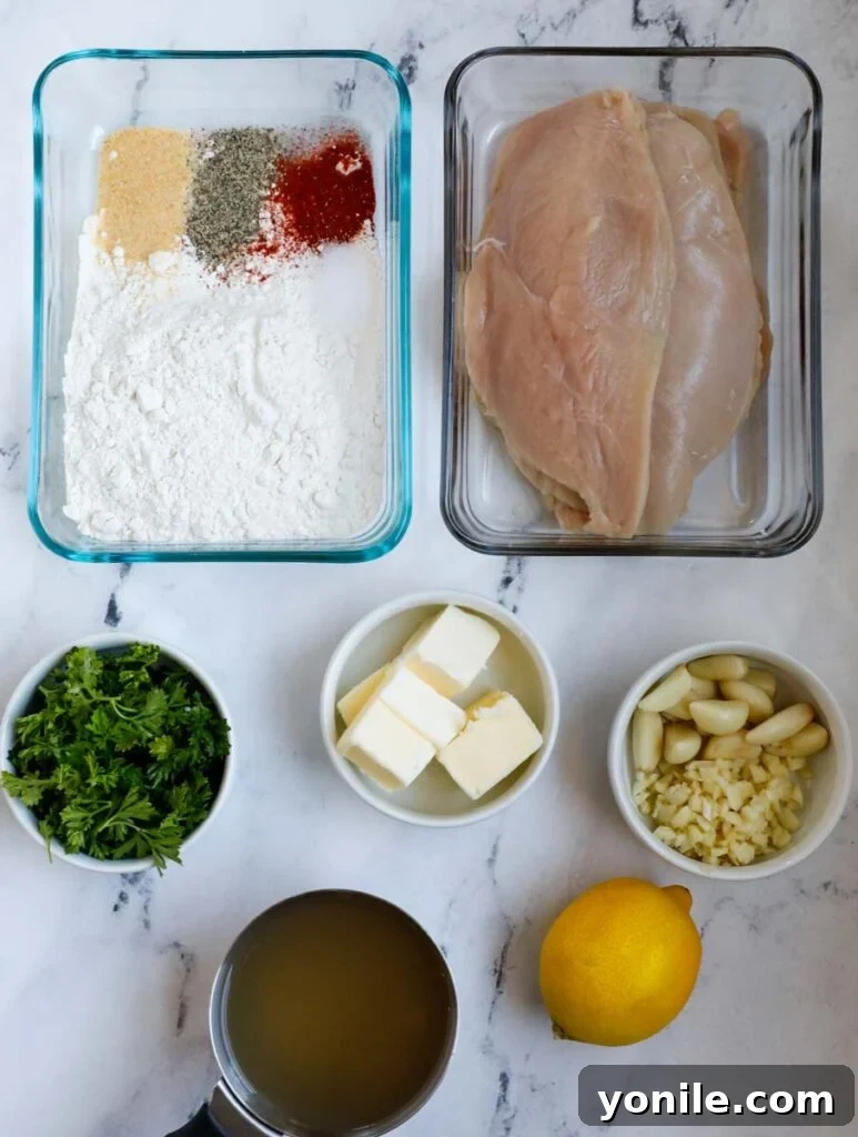 Top down shot of fresh ingredients laid out for making lemon and garlic chicken, including chicken, lemons, garlic, butter, and spices.