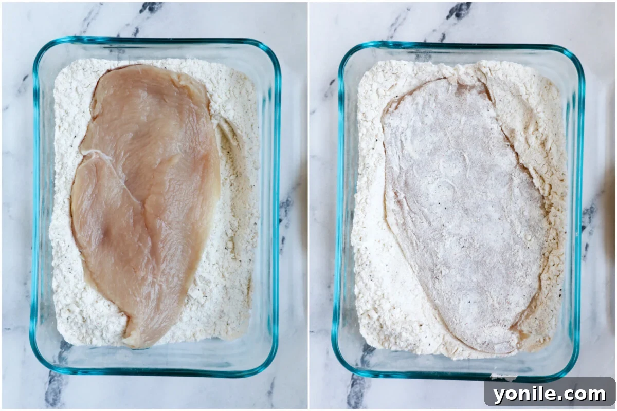 Top down shot of chicken pieces being coated in a seasoned flour mixture in a bowl.