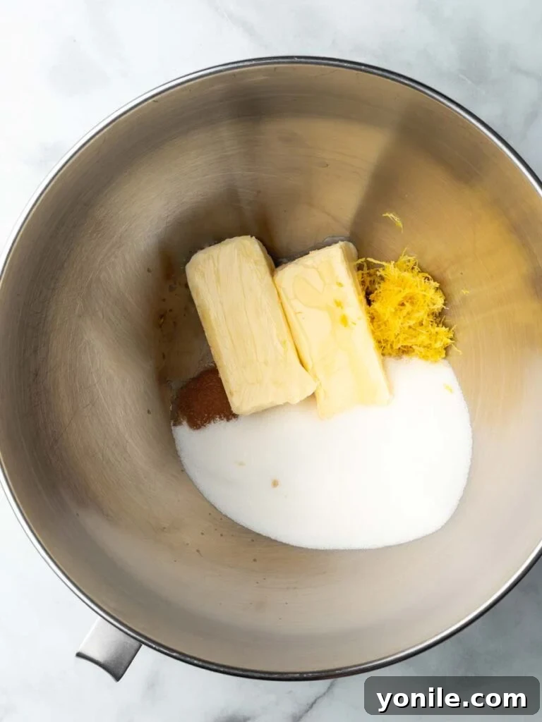 A mixing bowl filled with creamy yellow batter, containing butter, sugar, lemon zest, and vanilla extract, ready for the next steps in the Madeleine recipe.